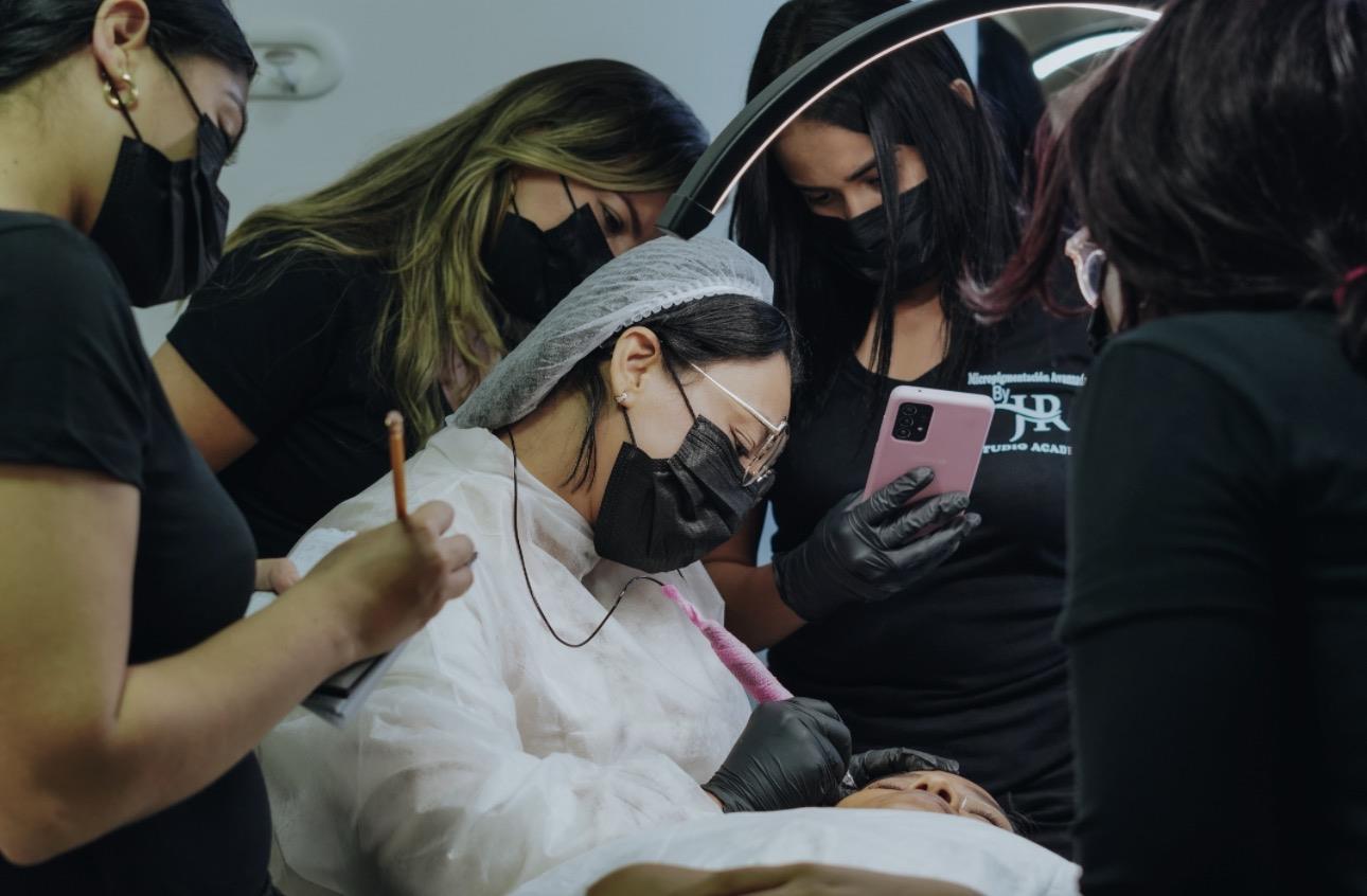 Alumnas observan una práctica de micropigmentación en la academia